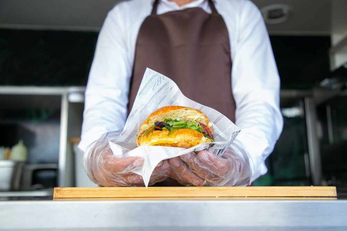 Takeaway server holding a takeaway burger